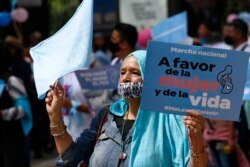 Seorang perempuan memegang plakat bertuliskan dalam bahasa Spanyol "In Favor of Women and Life," selama pawai anti-aborsi di Mexico City, Minggu, 10 Oktober. 3, 2021. (Foto AP/Ginnette Riquelme)