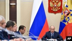 FILE - Russian President Vladimir Putin, right, presides over a cabinet meeting at the Novo-Ogaryovo residence outside Moscow, Russia.