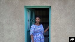 FILE—Jeanette Nyirabashyitsi, 45, stands in the doorway of her home at the Mybo reconciliation village in Nyamata, Rwanda, April 5, 2024.