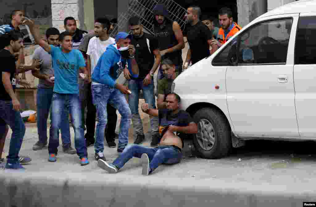 Palestinians try to evacuate a wounded man during clashes with Israeli troops at Qalandia checkpoint near the occupied West Bank city of Ramallah, Oct. 6, 2015.