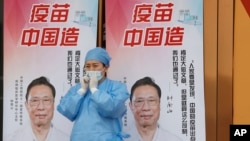 资料照：一名医护人员站在中国疫苗的广告前。（2021年4月9日）