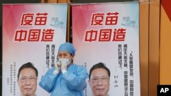 北京一位医护人员站在“疫苗中国造”宣传画前。（2021年4月9日）