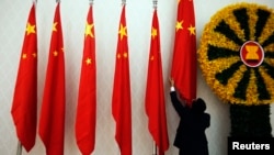 FILE PHOTO - An official adjusts Chinese flags before Chinese Premier Wen Jiabao arrives for the 21st ASEAN (Association of Southeast Asian Nations) and East Asia summits in Phnom Penh November 18, 2012. Southeast Asian nations displayed a rare show of unity on Sunday against China's sweeping maritime claims, calling for the first formal talks with Beijing over a sea dispute that has raised tensions and exposed deep divisions in the region. (Photo: REUTERS/Damir Sagolj)
