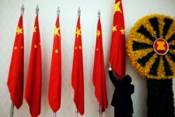 FILE - An official adjusts Chinese flags before Chinese Premier Wen Jiabao arrives for the 21st ASEAN (Association of Southeast Asian Nations) and East Asia summits in Phnom Penh November 18, 2012.