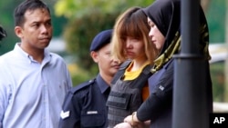 Vietnamese suspect Doan Thi Huong, second from right, in the ongoing assassination investigation, is escorted by police officers out from Sepang court in Sepang, Malaysia on Wednesday, March 1, 2017. Appearing calm and solemn, two young women accused of smearing VX nerve agent on Kim Jong Nam, the estranged half brother of North Korea's leader, were charged with murder Wednesday. (AP Photo/Daniel Chan) 