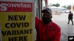 A petrol attendant stands next to a newspaper headline in Pretoria, South Africa, Nov. 27, 2021. 