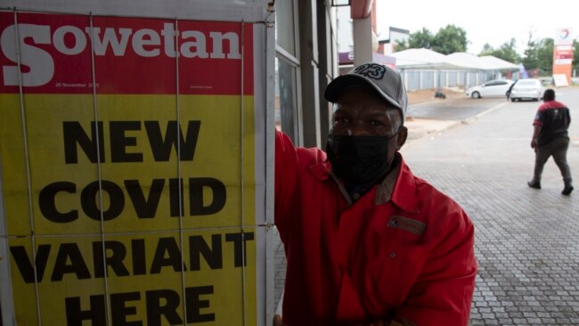 A petrol attendant stands next to a newspaper headline in Pretoria, South Africa, Nov. 27, 2021.
