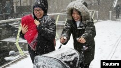 Two women make their way through snow in Canary Wharf, London, Britain, Feb. 27, 2018.