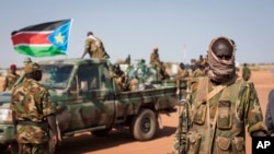 A South Sudanese government soldier stands with others near their vehicles, after government forces on Friday retook from rebel forces the provincial capital of Bentiu, in Unity State, South Sudan, Sunday, Jan 12, 2014.