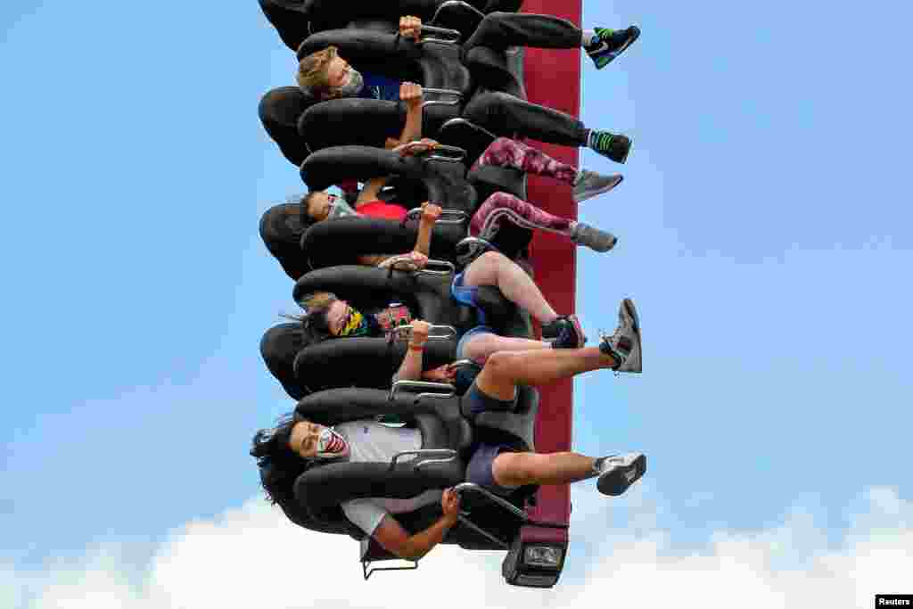 People wearing protective masks enjoy a ride in Thorpe Park, after it reopened following the coronavirus disease (COVID-19) outbreak, in Chertsey near London.