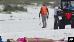 Madison Smith of Cincinnati lies in the sun on the beach in Perdido Key, Fla., as oil spill cleanup workers search for tar balls a year after the Deepwater Horizon disaster, April 19 2011