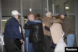 Family and friends embrace Bahram Mechanic (in the blue jump suit) and Khosrow Afghahi (in the tan jacket) at Federal Detention Center Houston, Texas, Jan.17, 2016. Several Iranian-Americans held in U.S. prisons after being charged or convicted for sanctions violations have been released under a prisoner swap.