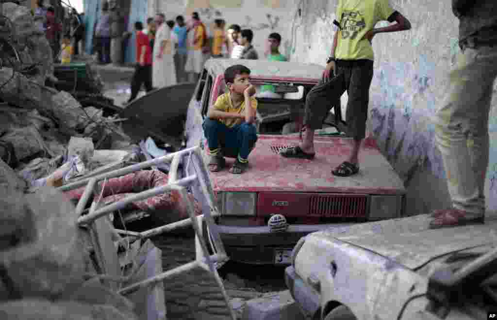 Palestinians look at the damage of a destroyed house where five members of the Ghannam family were killed in an Israeli missile strike in Rafah refugee camp, southern Gaza Strip, July 11, 2014.