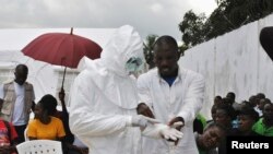 A volunteer health worker practices using a personal protective equipment (PPE) suit at a newly-constructed Ebola virus treatment centre in Monrovia, Liberia. Source: Reuters