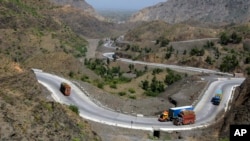FILE - Afghanistan-bound trucks pass through a valley while moving toward the Torkham border crossing in Torkham, Pakistan, Saturday, June 18, 2016. 