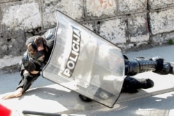 Pripadnik crnogorske policije pritiže se sa zemlje nakon guranja sa demonstrantima koji se protive ustoličenju mitropolita SPC Joanikija u Cetinju, 4 septembra 2021. (Foto: Rojters, Stevo Vasiljević)