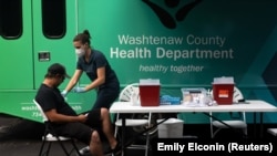 Seorang perawat bersiap menyuntikkan vaksin COVID-19 kepada seorang pria dalam sebuah acara vaksinasi massal di Ypsilanti, Michigan, Sabtu, 7 Agustus 2021. (Foto: Emily Elconin/Reuters)