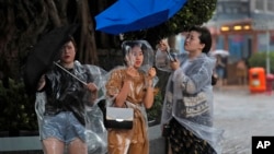 People hold umbrellas against the strong wind caused by tropical storm Pakhar near the waterfront of Victoria Habour in Hong Kong, Aug. 27, 2017.