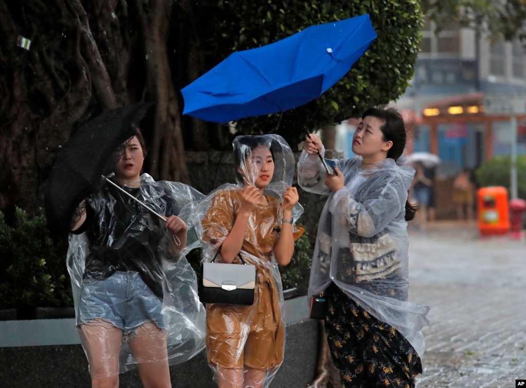 2017年8月27日，在香港维多利亚港附近，人们在热带风暴的强风袭击下。