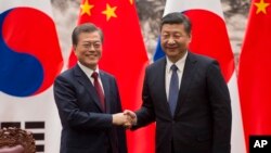 South Korean President Moon Jae-in, left, and Chinese President Xi Jinping shake hands at the end of a signing ceremony at the Great Hall of the People, in Beijing, China, Dec. 14, 2017.