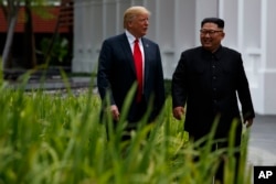 FILE - President Donald Trump walks with North Korean leader Kim Jong Un on Sentosa Island, Tuesday, June 12, 2018, in Singapore.