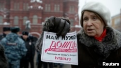 FILE - A protester holds a flyer reading "We need Dozhd" during a rally in support of the independent television station Dozhd (TV Rain), in Moscow, February 8, 2014.