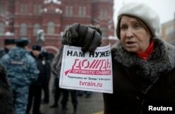 FILE - A protester holds a flyer reading "We need Dozhd" during a rally in support of the independent television station Dozhd (TV Rain), in Moscow, February 8, 2014.