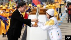 El primer ministro surcoreano, Lee Nak-yon (izquierda) entrega la llama olímpica a la estrella de patinaje artístico You Young, en Incheon, Corea del Sur, el miércoles, 1 de noviembre de 2017.