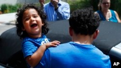 FILE - Ever Reyes Mejia of Honduras carries his son to a vehicle after being reunited and released by United States Immigration and Customs Enforcement in Grand Rapids, Mich., July 10, 2018. The Trump administration is one month past a deadline to reunite the rest of the separated families.
