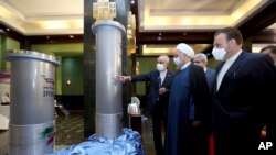 Presiden Iran Hassan Rouhani, kedua dari kanan, mendengarkan keterangan kepala Organisasi Energi Atom Iran Ali Akbar Salehi saat mengunjungi pameran pencapaian nuklir baru Iran di Teheran, Iran, 10 April 2021. (Kantor Kepresidenan Iran via AP, File)