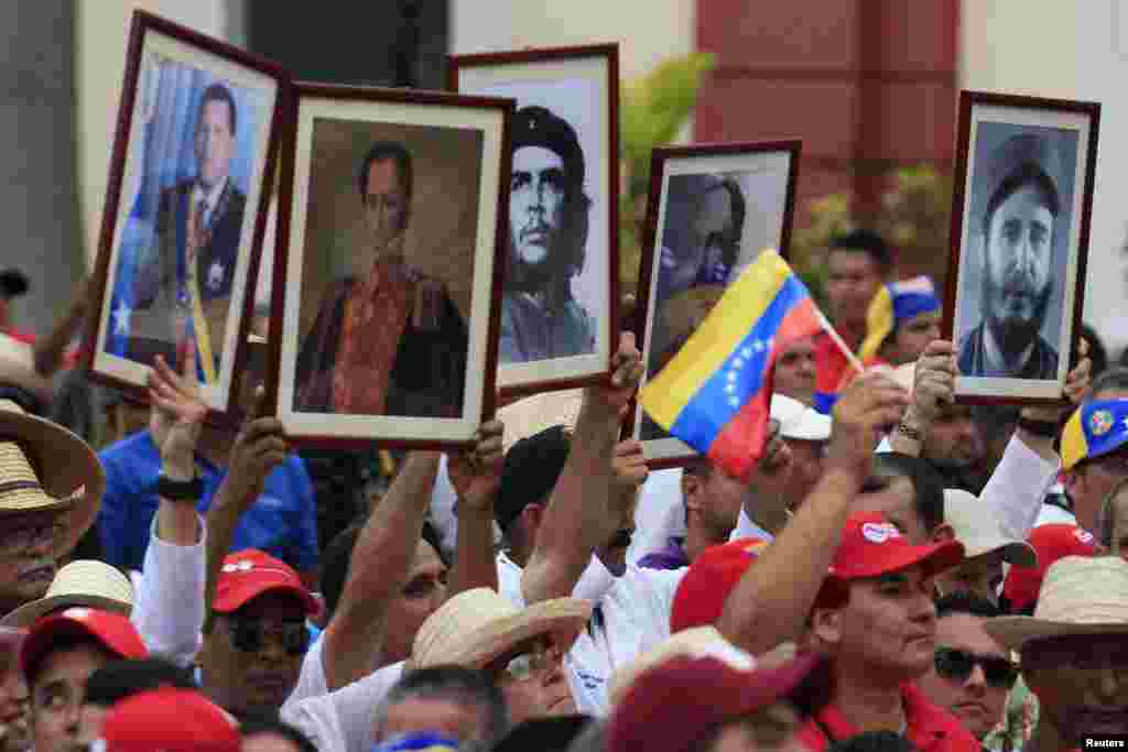 Cuban doctors hold up framed pictures (L-R) of late President Hugo Chavez, Venezuela's National hero Simon Bolivar, Ernesto 'Che' Guevara, Cuban national hero Jose Marti and Fidel Castro during a march of farmers in support of Venezuela's President Nicolas Maduro, Caracas, Feb. 26, 2014.