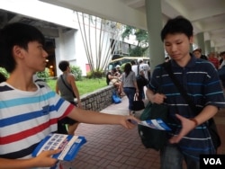 普教中學生關注組副主席網名「郭奉孝」(左)向香港市民派發反對普教中傳單。（美國之音湯惠芸）
