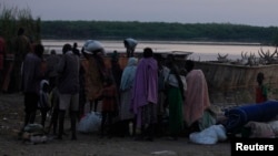 People displaced by fighting in Bor county stand by their belongings after arriving in the port of Minkaman, Awerial county, Lakes state, South Sudan, Jan. 14, 2014.
