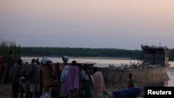 People displaced by the fighting in Bor county, stand by their belongings after arriving in the port of Minkaman, in Awerial county, Lakes state, in South Sudan, Jan. 14, 2014.