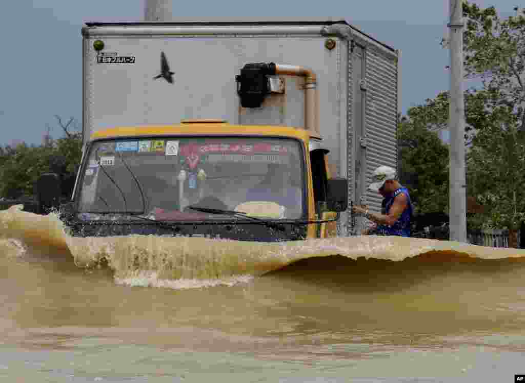 A truck driver braves the raging floodwaters brought about by Typhoon Nari along a highway at San Ildefonso township, Bulacan province, north of Manila, Philippines. At least 13 people have been killed after the storm battered across the northern Philippines, flooding villages and farms in the country’s major rice-growing region, officials said.