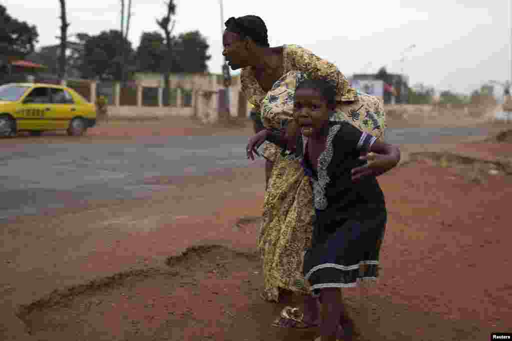 A mother holds her child while attempting to take cover as repeated gun shots are heard close to Miskine district during continuing sectarian violence in the capital Bangui, Central African Republic, Jan. 28, 2014.