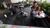 Para pengunjung sebuah kafe di Gelora Bung Karno duduk dalam jarak tertentu dalam upaya mencegah penyebaran virus corona, Jakarta, 26 Maret 2020. (Foto: Dita Alangkara/AP)