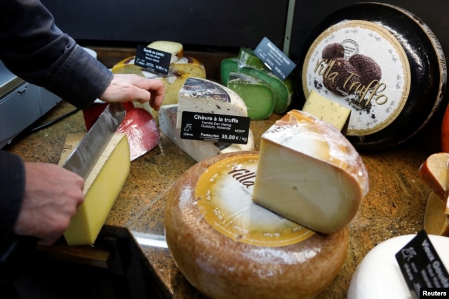 FILE - A cheesemonger cuts a large piece of Comte cheese at Beaufils affineur in Paris as France celebrates national Fromage day to protect real raw milk cheese, France, March 27, 2019. (REUTERS/Charles Platiau)