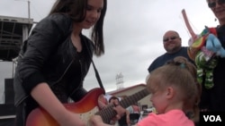 One of Ally's young fans takes a turn on her guitar. (G. Flakus/VOA)