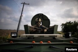 An agent with the U.S. Border Patrol Tactical Unit (BORTAC) holds his weapon from an armored vehicle ahead of exercises in Mission, Texas, Nov. 8, 2018.