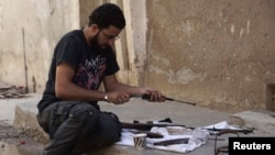 A Free Syrian Army member cleans his weapon on a street in Deir al-Zor, July 7, 2013.