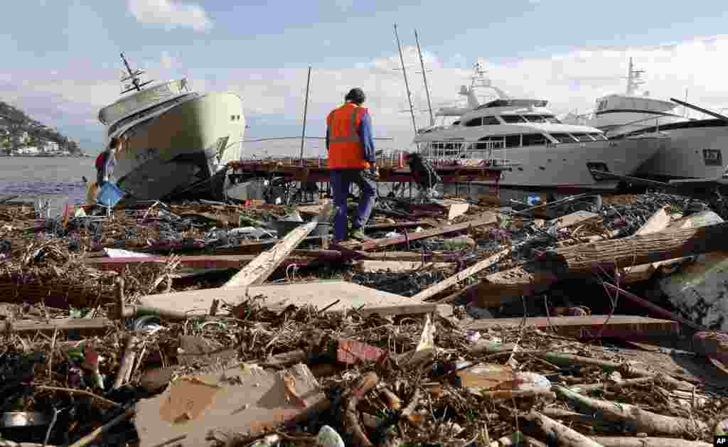 People clean up debris that washed ashore from yachts and boats, a day after a storm, in Rapallo, Italy.