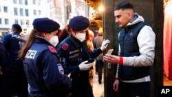 Oficeret e policisë kontrollojnë statusin e vaksinimit të personave në një treg të Krishtlindjeve në Vjenë, Austri (19 nëntor 2021)