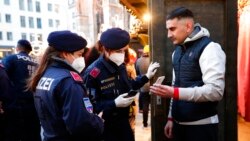 Police officers check the vaccination status of visitors during a patrol on a Christmas market in Vienna, Austria, Nov. 19, 2021. Austrian Chancellor Alexander Schallenberg says the country will go into a national lockdown to contain a fourth wave of coronavirus cases.