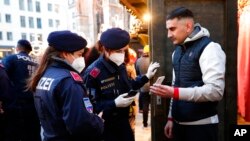Police officers check the vaccination status of visitors during a patrol on a Christmas market in Vienna, Austria, Nov. 19, 2021. Austrian Chancellor Alexander Schallenberg says the country will go into a national lockdown to contain a fourth wave of coro