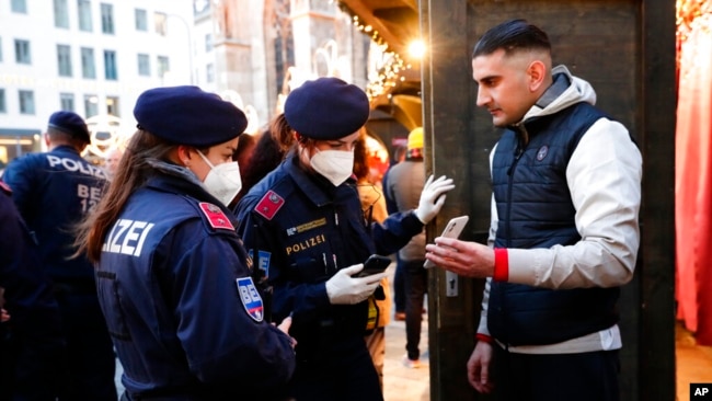 Police officers check the vaccination status of visitors during a patrol on a Christmas market in Vienna, Austria, Nov. 19, 2021. Austrian Chancellor Alexander Schallenberg says the country will go into a national lockdown to contain a fourth wave of coronavirus cases.