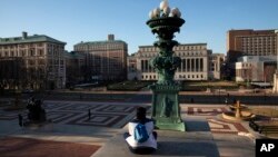 A woman sits on the Columbia University campus, Monday, March 9, 2020, in New York. Colleges nationwide, including Columbia, are shutting down campuses with plans to continue instruction online. (AP Photo/Mark Lennihan)