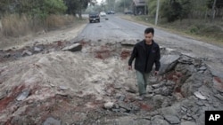 A Thai man walks though a bomb crater near Sisaket, Thailand, near the border with Cambodia, Monday, Feb. 7, 2011. Troops of Cambodia and Thailand continue to clash near the 11th century Preah Vihear temple.