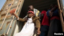 Un homme aide une personne aveugle à descendre d'un camion à la frontière du Cameroun et de la Centrafrique, le 8 mars 2014.