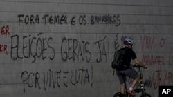 A cyclist passes graffiti that reads in Portuguese "Get out Temer and bankers. General elections now!" at a traffic light at the bus station in Brasilia, Brazil June 12, 2017.